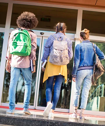 Students with backpacks walking into a school