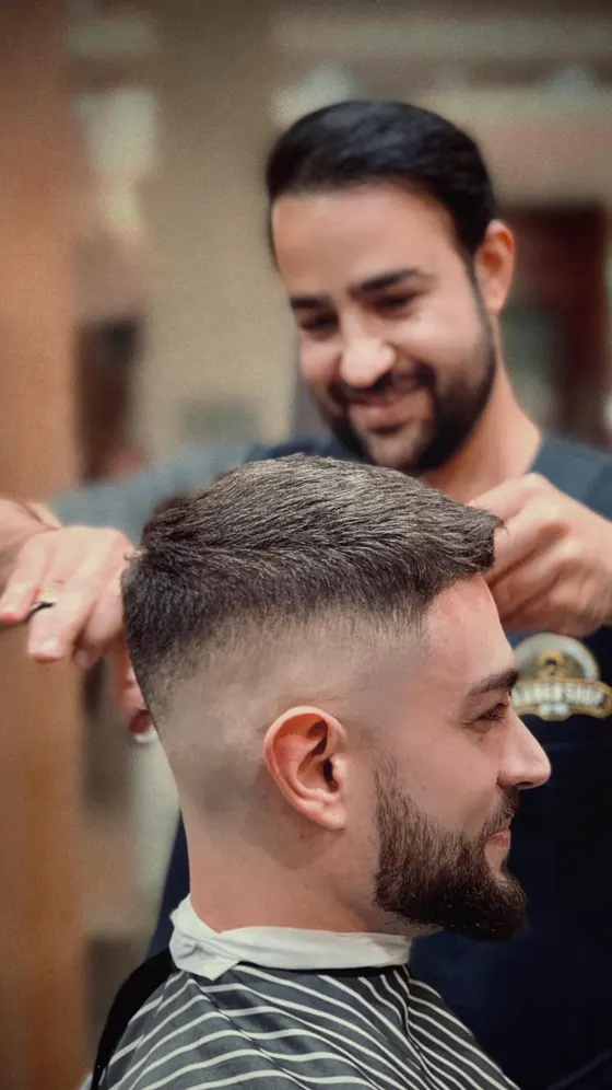 A barber in a shop tee working through the sides