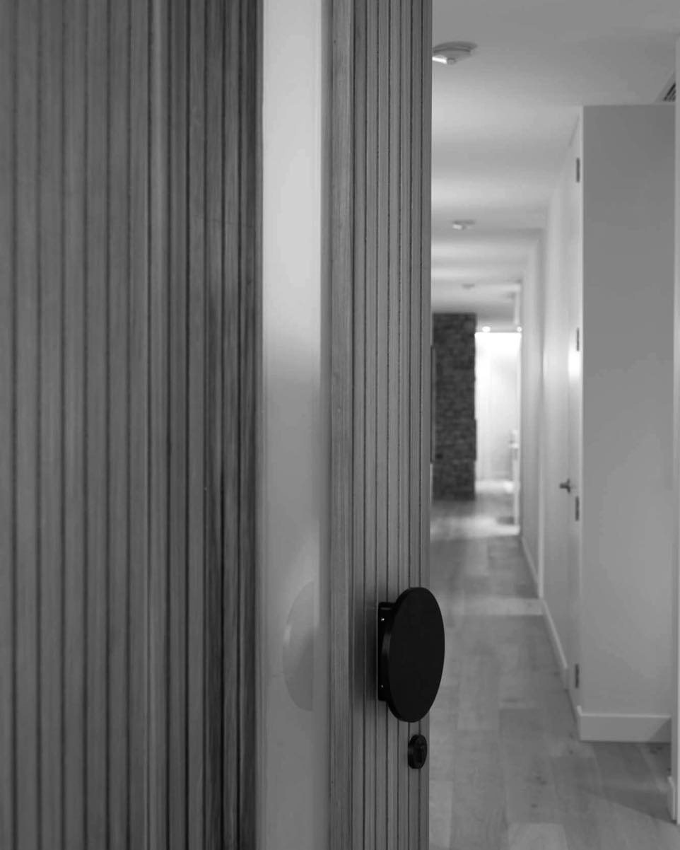 Hallway detail showing a fluted timber feature wall running the length of the corridor beside a flush cabinetry line.