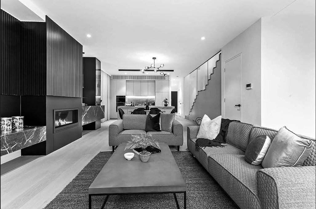 Living room with a dark fluted feature wall, integrated fireplace and a staircase rising beyond the seating zone.