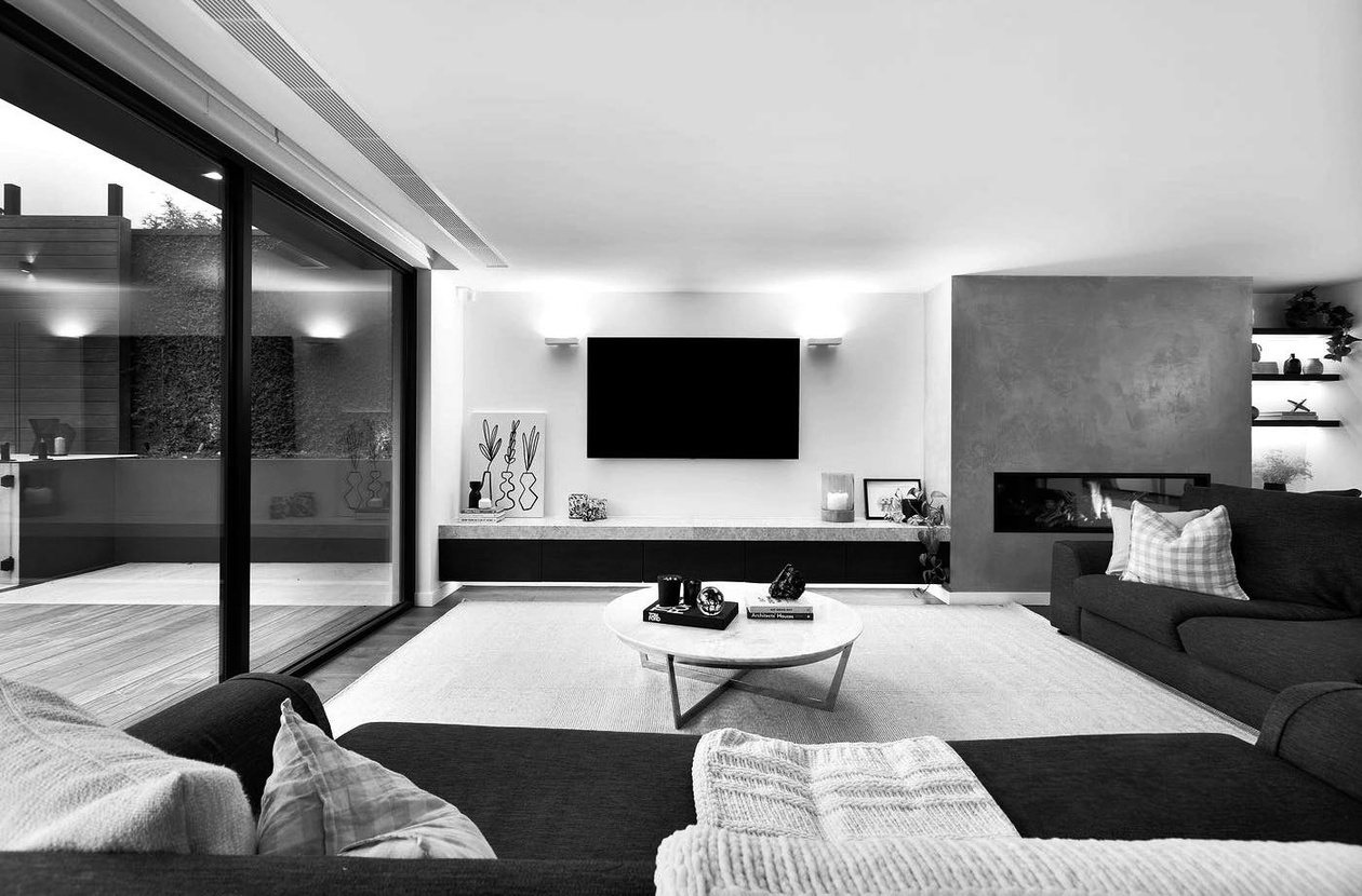 Second lounge area with a stone hearth, wall-mounted television and built-in joinery either side of the opening.
